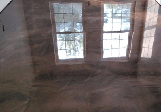 Room interior with floor covered in protective plastic sheeting reflecting light from a double-hung window, in preparation for work.
